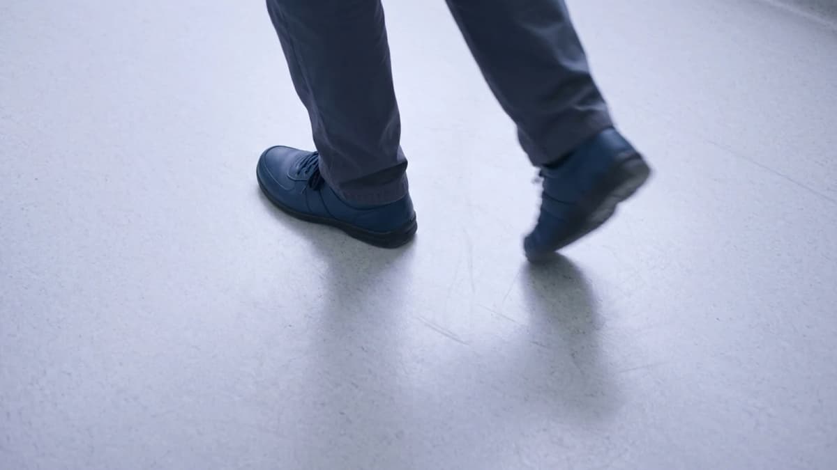 Two feet mid-stride seen from above on pale clinic flooring