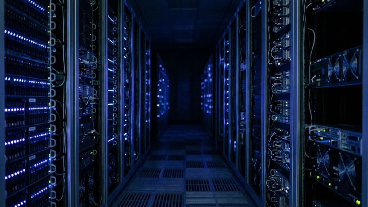 A data centre aisle between server racks lit by rows of small blue indicator lights
