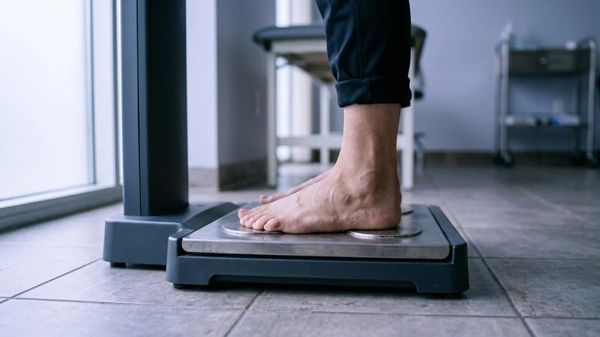 Bare feet standing on the metal footplates of a body composition analyser on a tiled floor