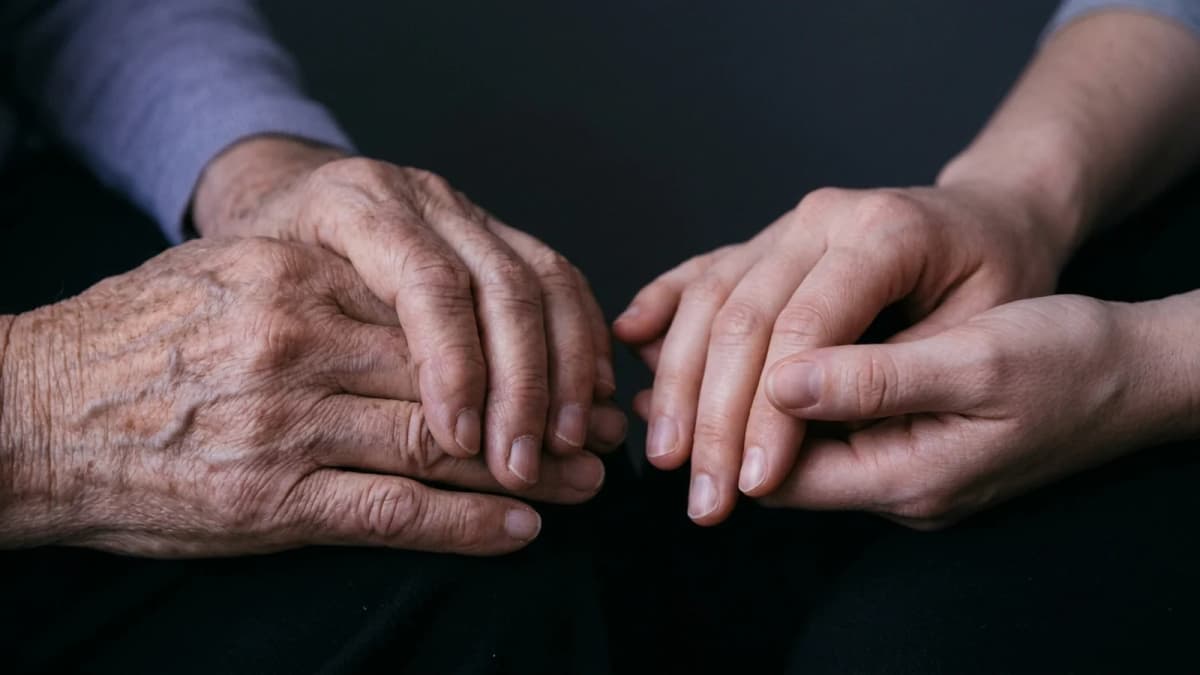 Two pairs of hands of different ages held side by side against a dark background