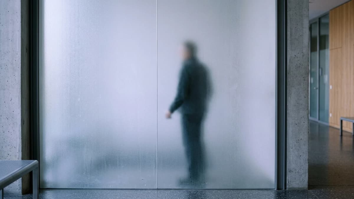 A frosted glass partition with a blurred silhouette standing behind it